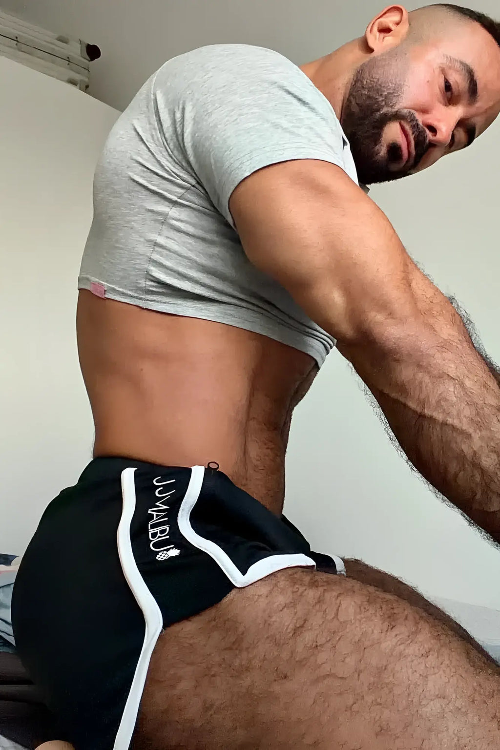 Black athletic shorts with white side stripes and small logo on left leg paired with muscle-fit crop tee free verse