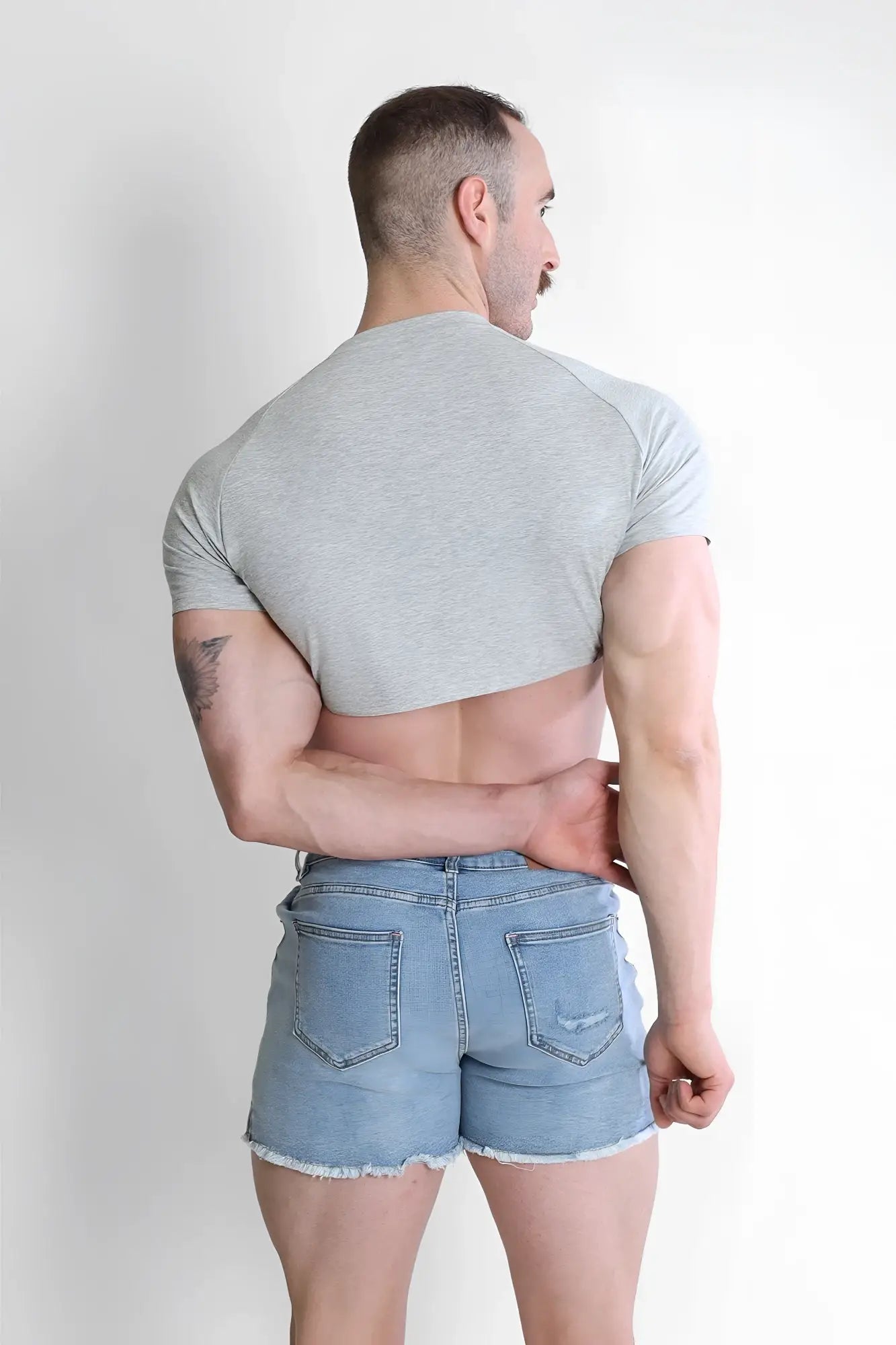 Man wearing a gray muscle-fit crop tee with raglan sleeves designed for a stylish athletic look