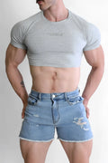 Gray muscle-fit crop tee with subtle chest text paired with distressed blue denim shorts for casual wear