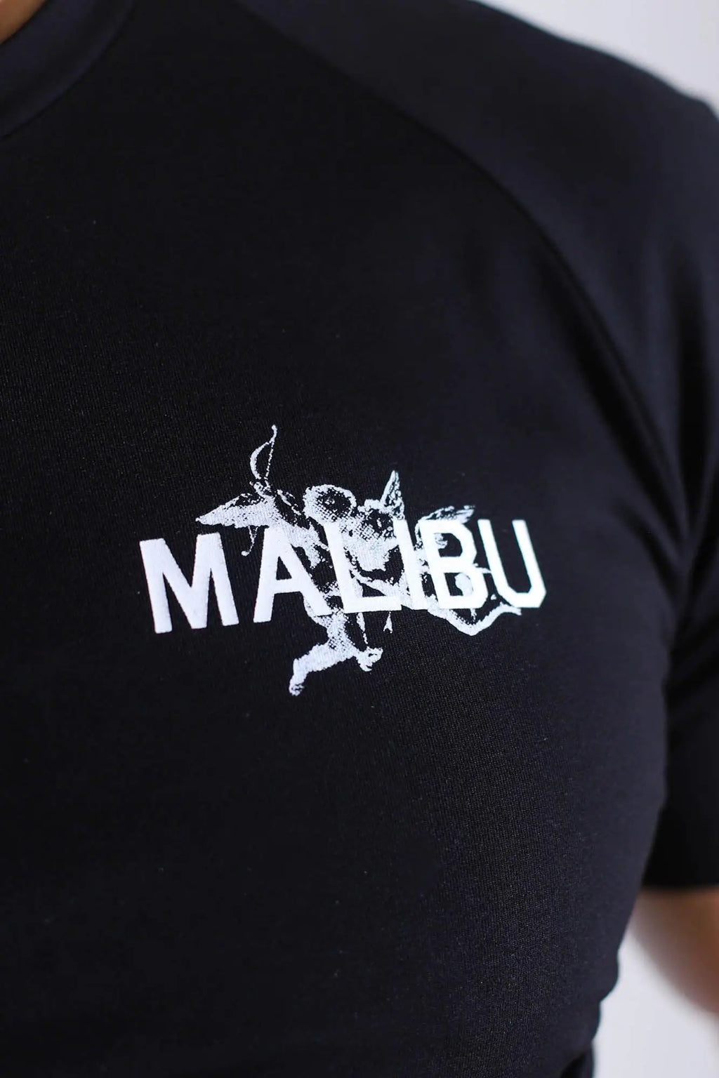 Black muscle-fit crop tee with short sleeves featuring a white distressed malibu graphic and angelic figure