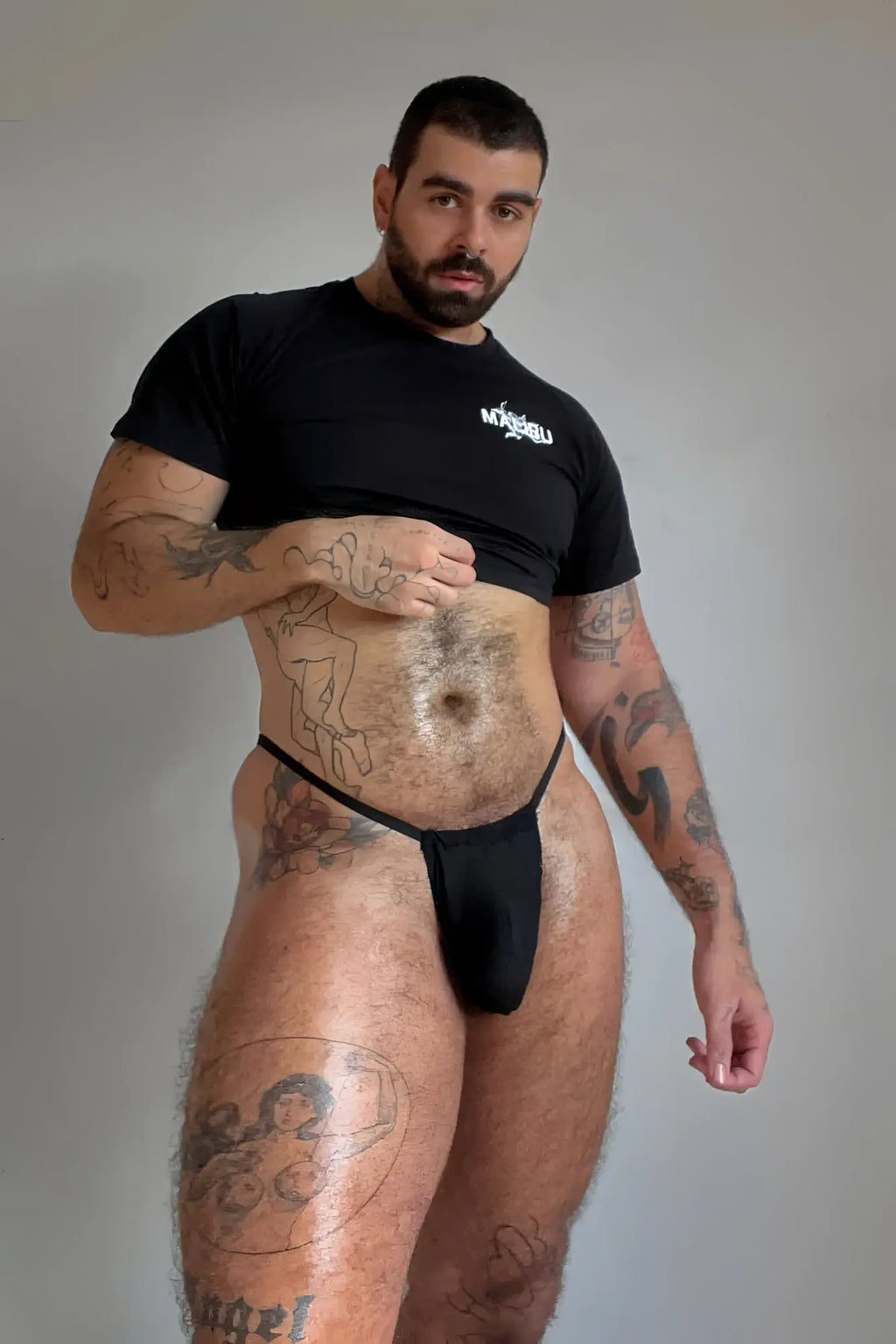 Black thong with a simple minimalist design and no visible branding paired with muscle-fit crop tee malibu angel