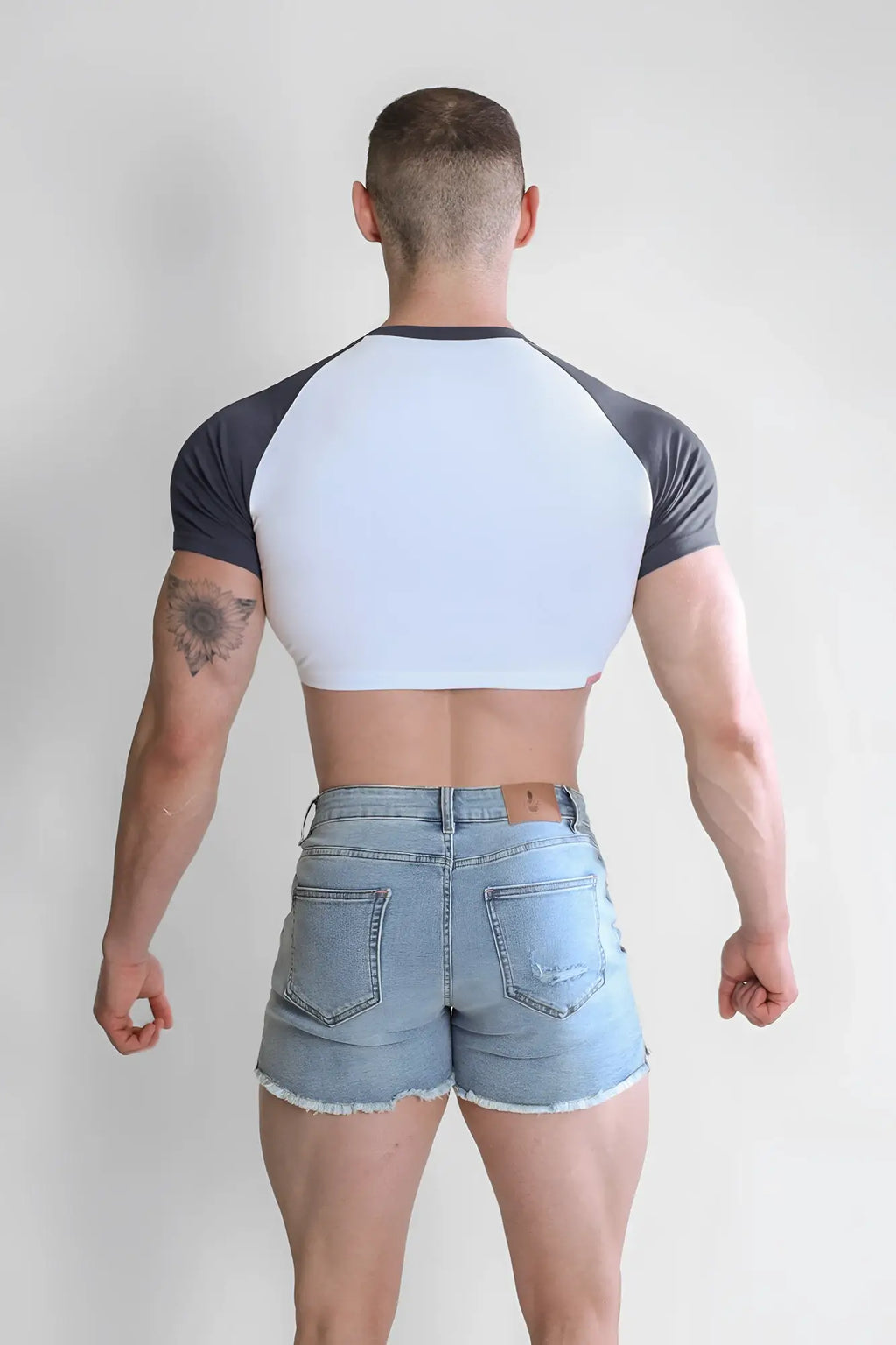 A man wearing a white and dark gray muscle-fit crop tee with raglan sleeves from rebel bloom
