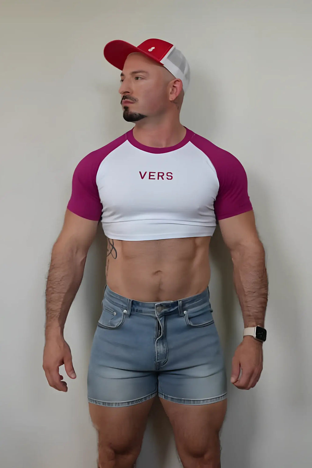 A man wearing a white and magenta muscle-fit raglan crop tee with vers printed in maroon across the chest