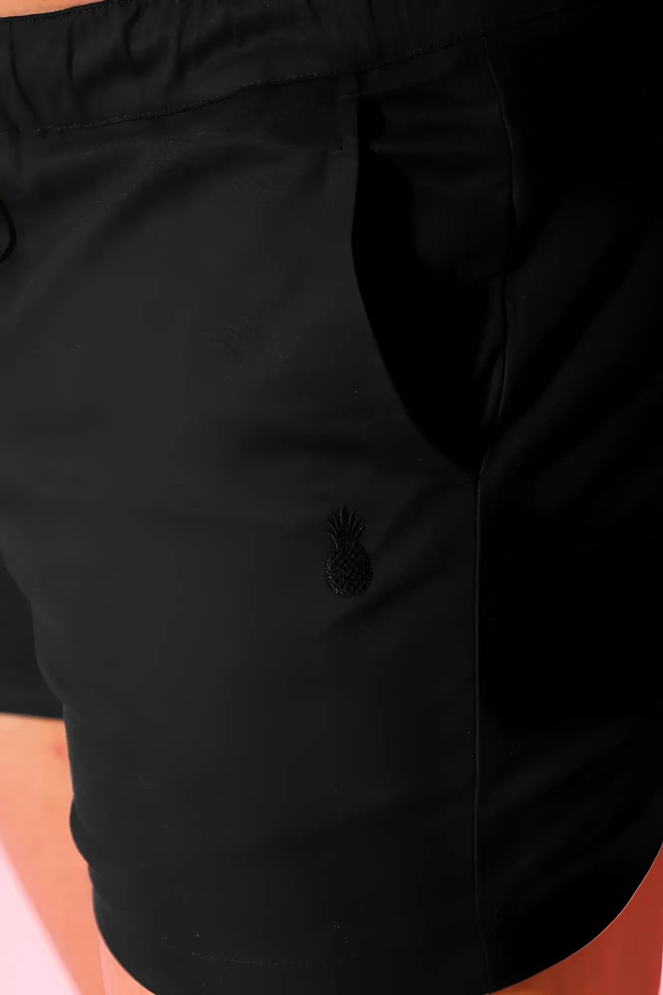 Muscle-fit men’s 4 inch stretchy jet black chino shorts with subtle embroidered pineapple logo on front