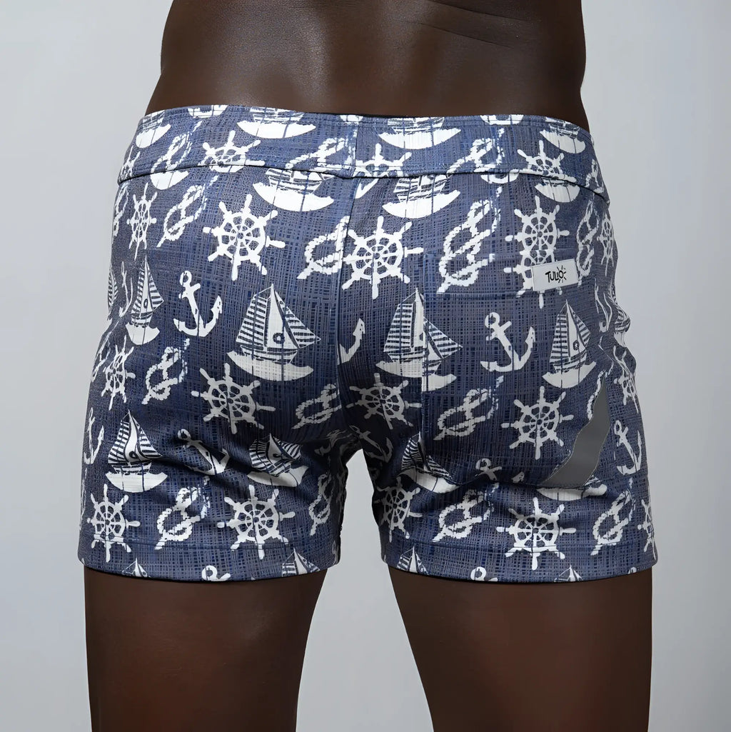 Nautical linen texture shorts in blue featuring white ship wheels anchors and sailboats in a repeating pattern