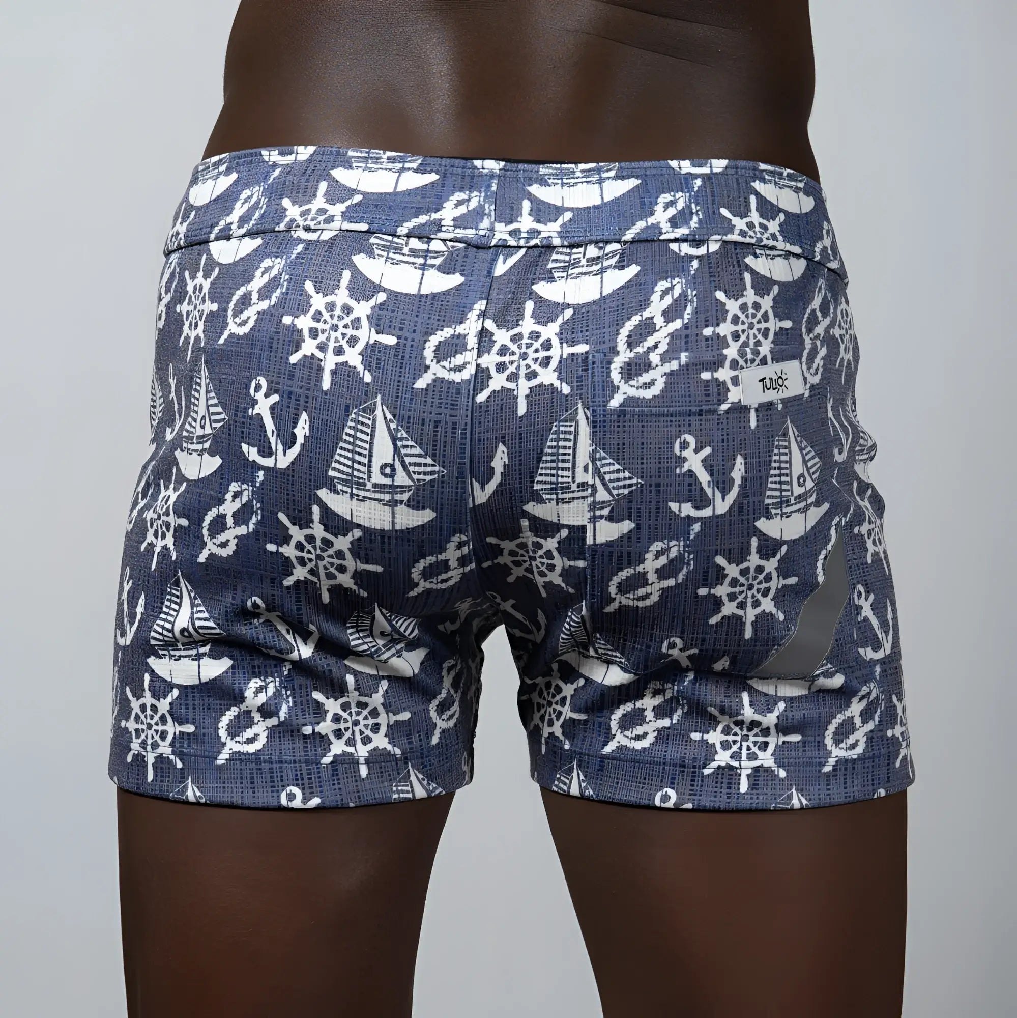 Nautical linen texture shorts in blue featuring white ship wheels anchors and sailboats in a repeating pattern