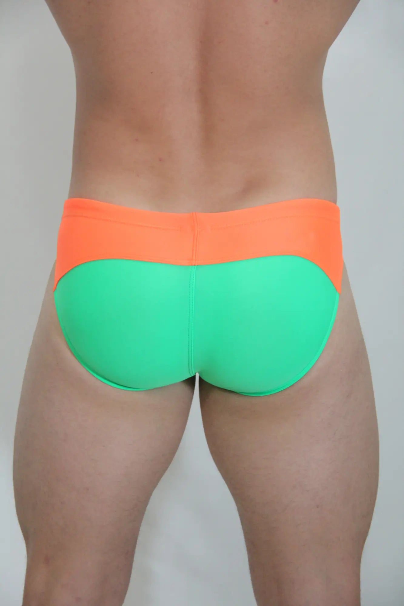 Bright orange and neon green two-tone neon curved swim brief with stretchy fabric for vibrant beachwear