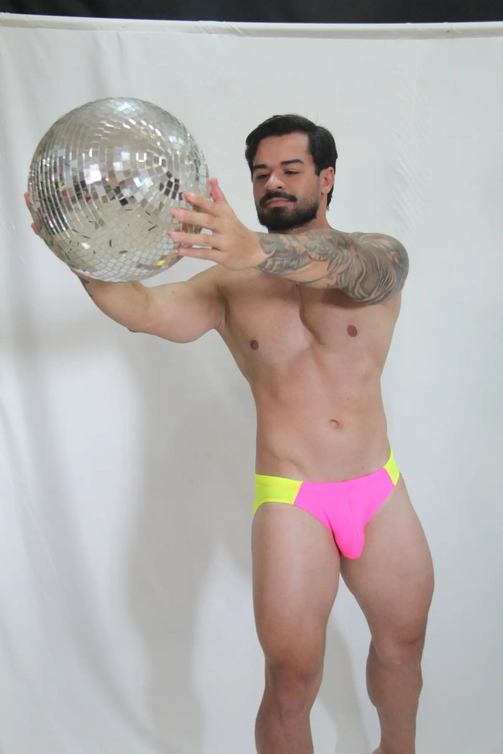 Shiny silver disco ball with mirrored facets reflecting light for a vibrant neon curved swim brief backdrop
