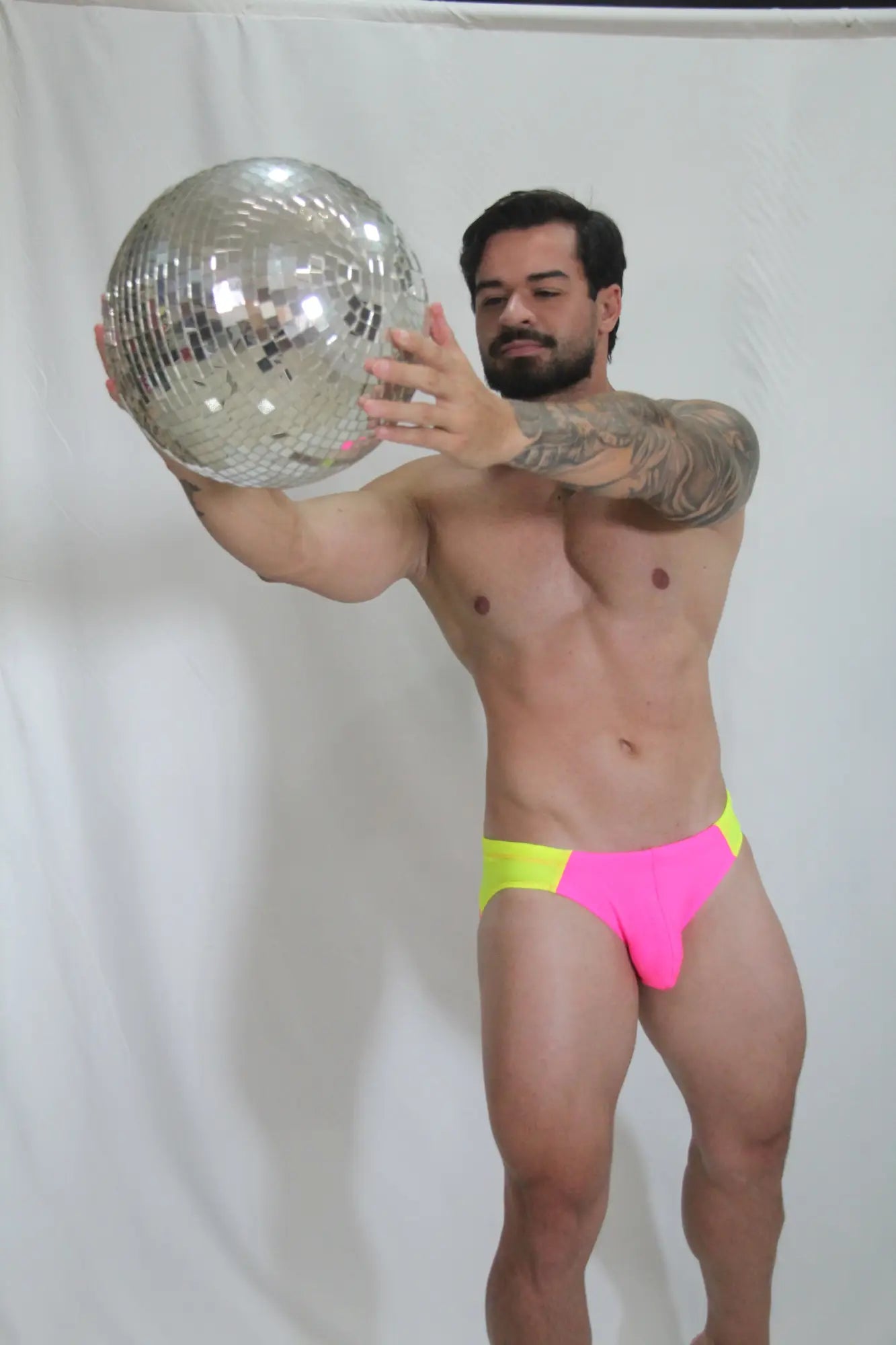 Neon curved swim brief with shiny silver disco ball mirrored facets reflecting light