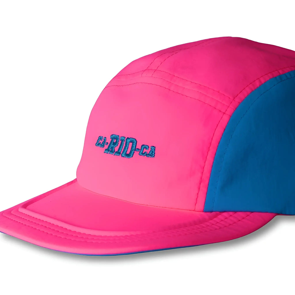 A vibrant pink and blue neon dream bike cap hat with teal ca-pid-ca embroidery on a five-panel design