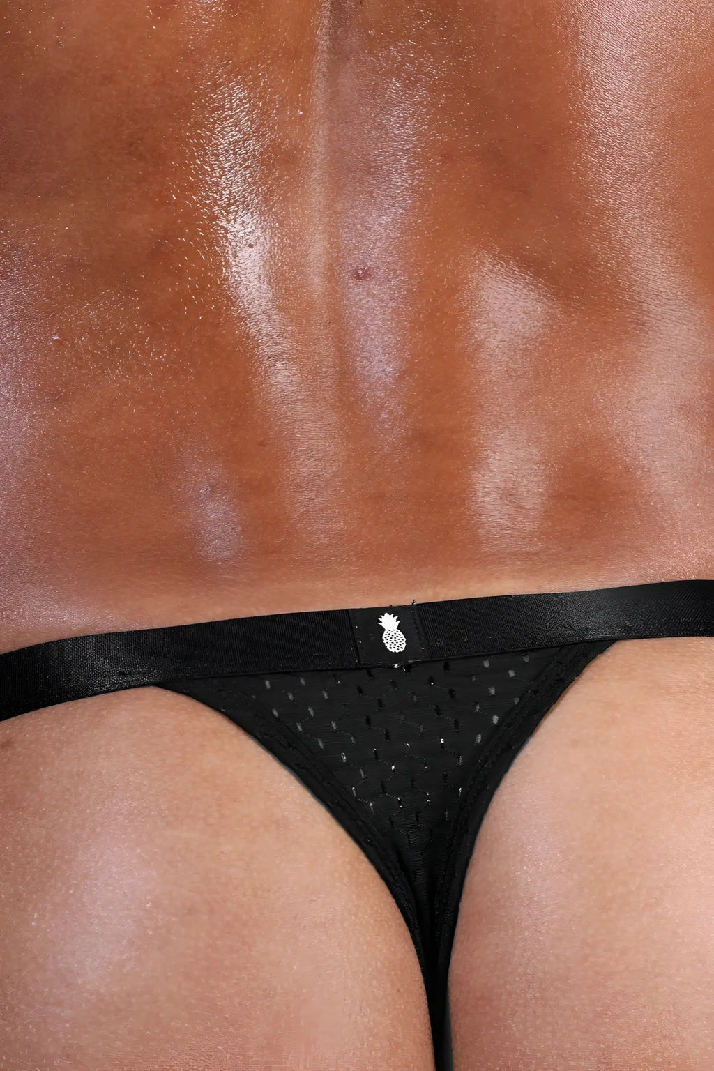 Now-or-never mesh thong black featuring black mesh material and a small silver pineapple emblem on the waistband
