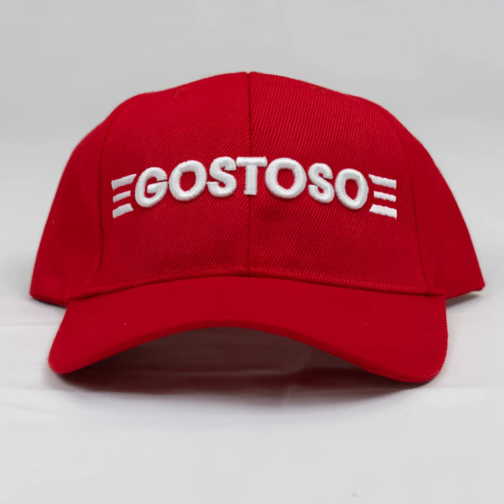 A vibrant red baseball hat with bold white 3D puff gostoso stripes logo embroidered on the front panel