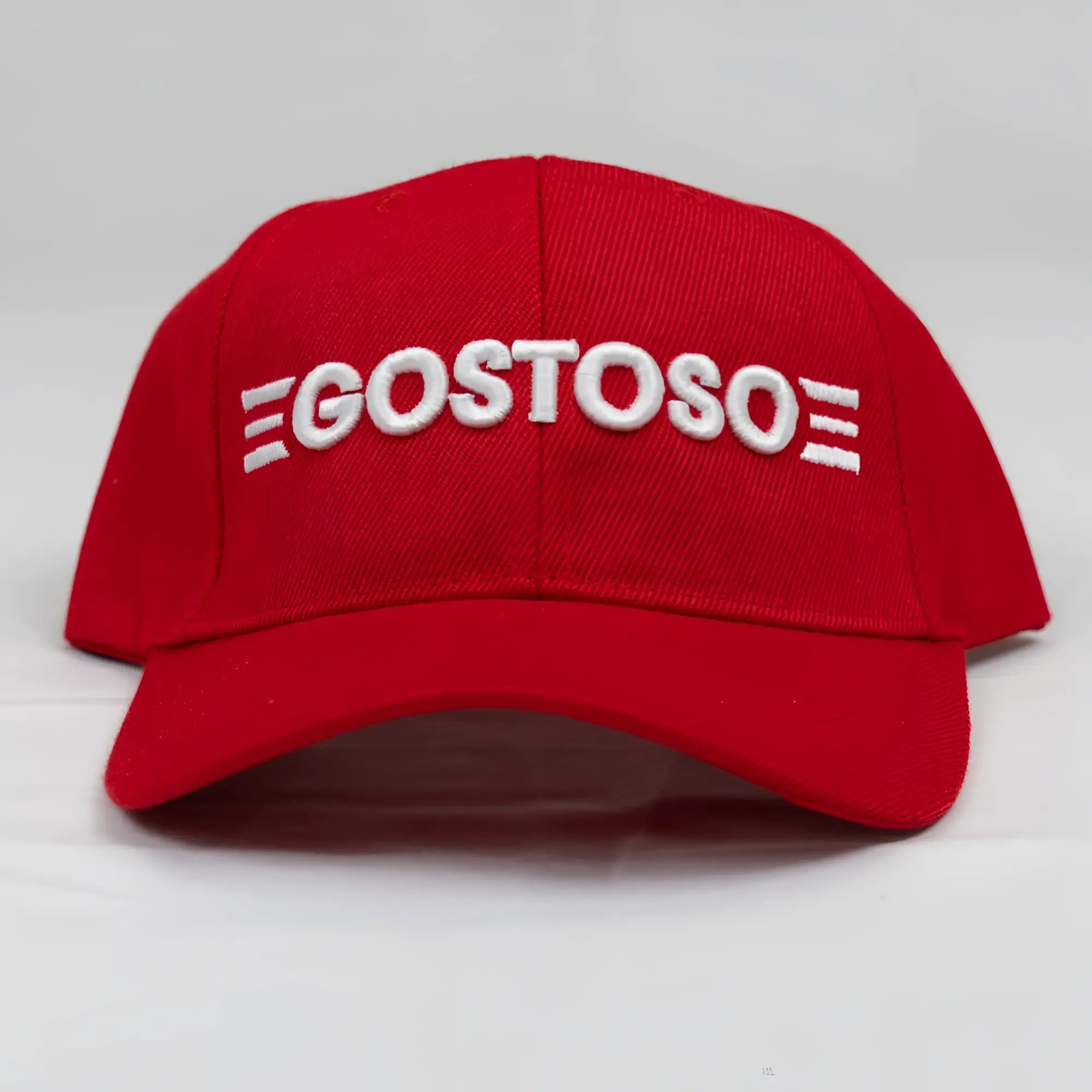 A vibrant red baseball hat with bold white 3D puff gostoso stripes logo embroidered on the front panel