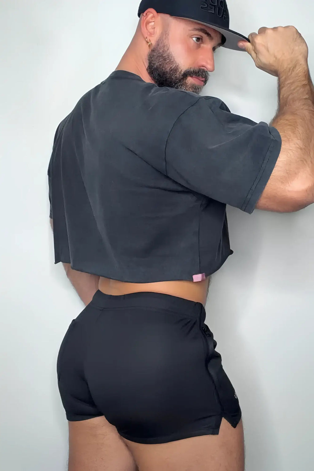 Back side of a black cropped t-shirt with a small pink tag and obsidian black for-the-night 2 inch gym short shorts