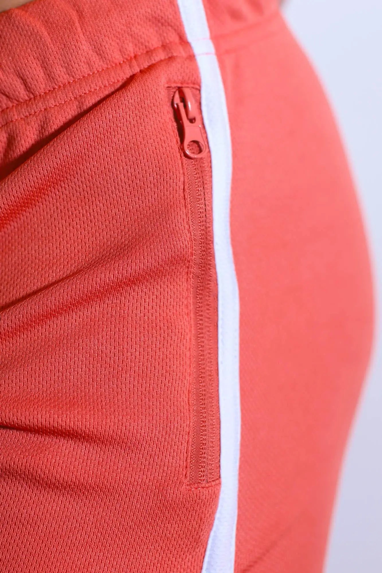 Coral-colored for-the-night 4 inch gym short shorts with white side stripe and matching zipper pocket in tangerine