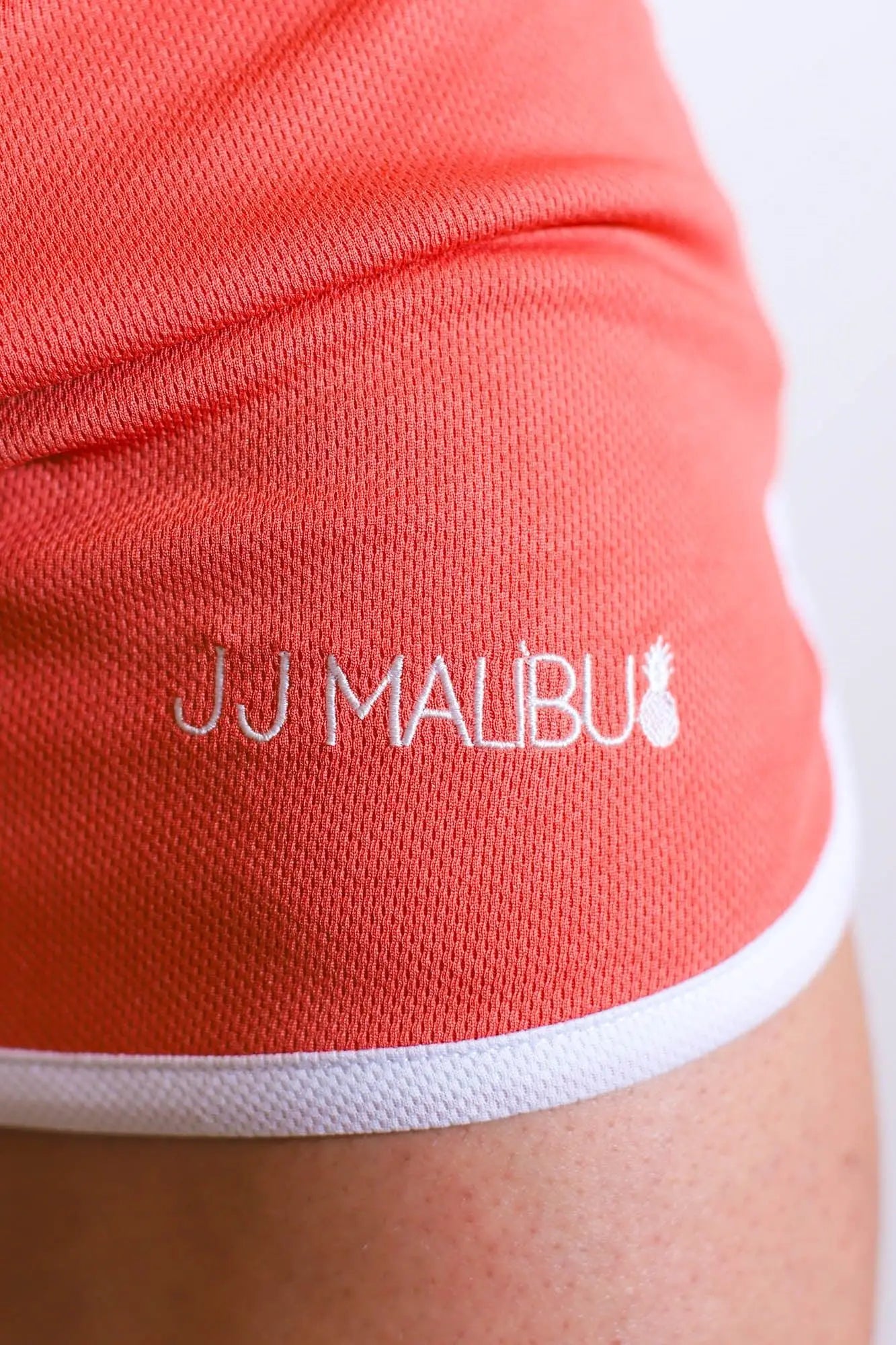 Coral-colored for-the-night 4 inch gym short shorts with white trim and jj malibu logo embroidered on the side