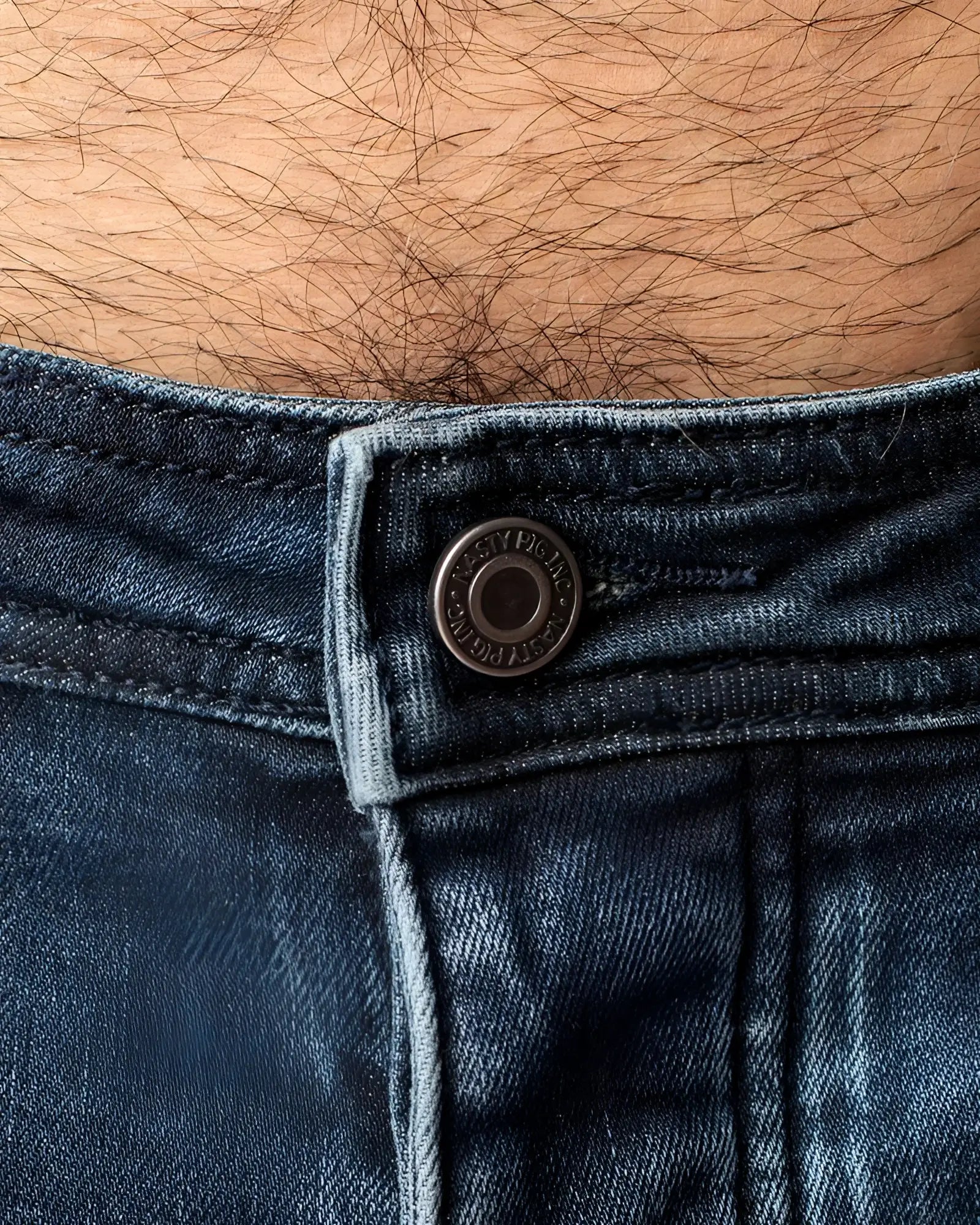 Dark blue denim jeans np jean with metallic button featuring embossed text on the front waistband