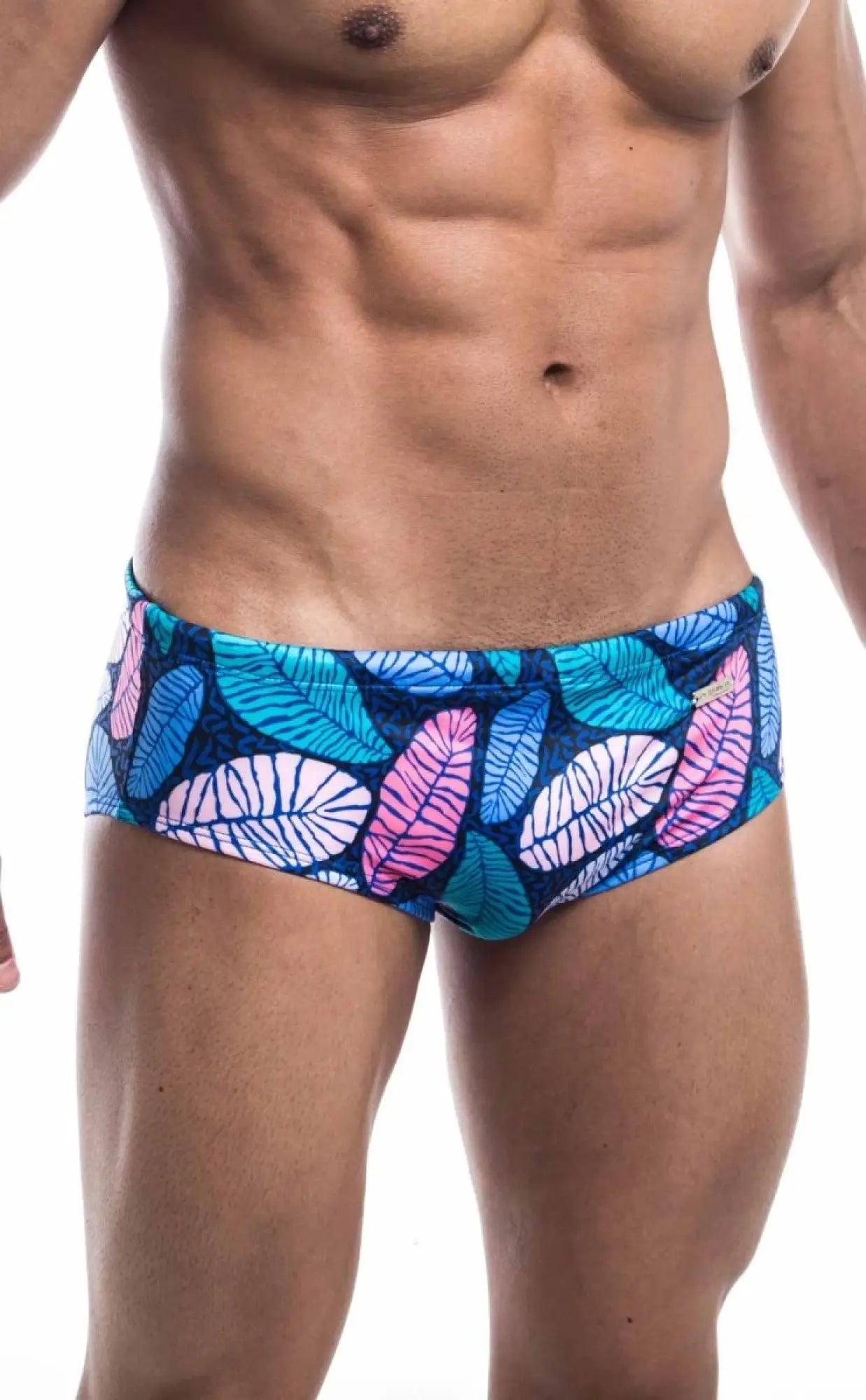 Oceanico swim brief featuring vibrant tropical leaf pattern in pink teal and white on a dark blue base