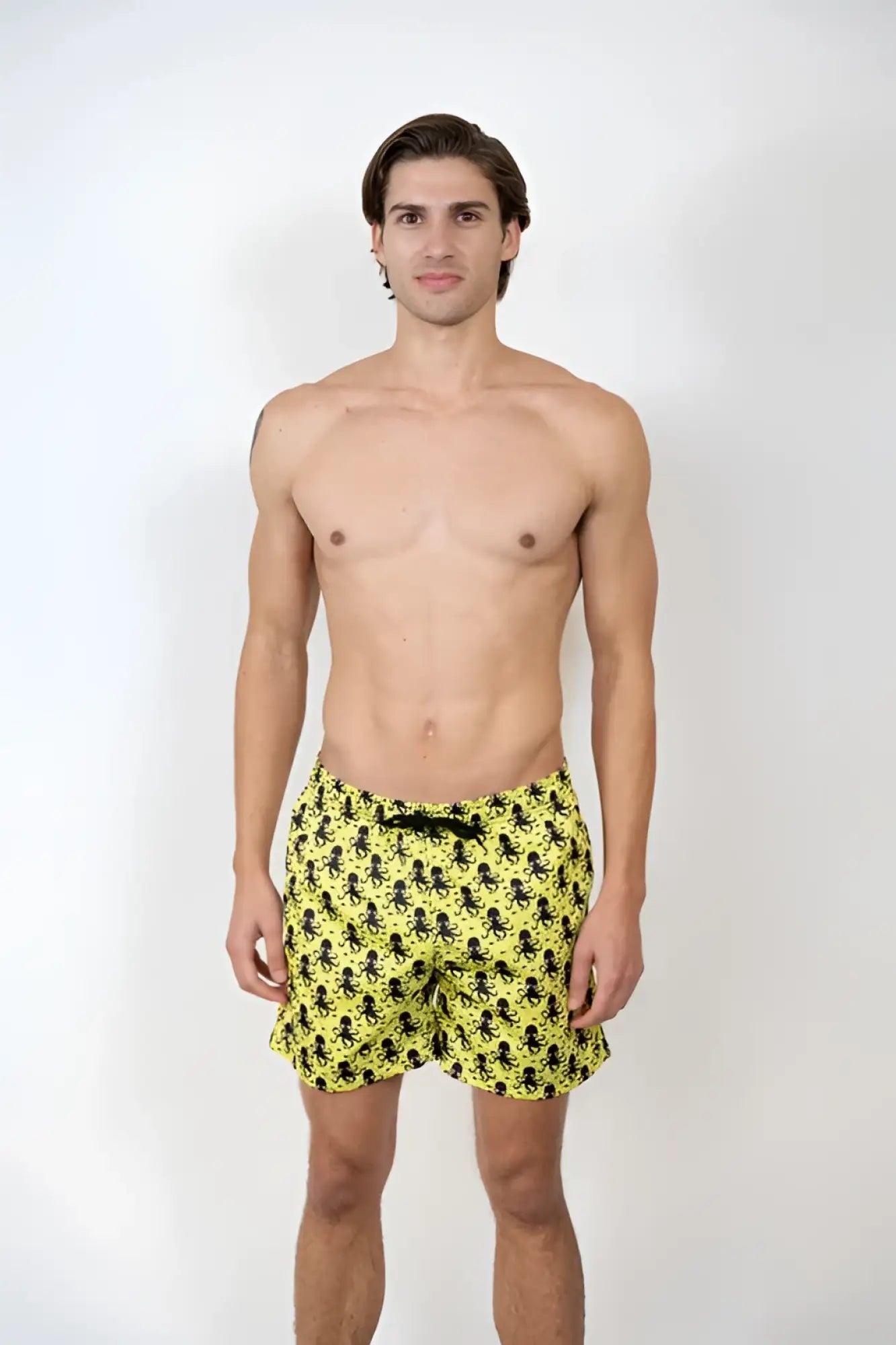 Bright yellow swim shorts with a repeating black octopus pattern perfect for beach and pool use