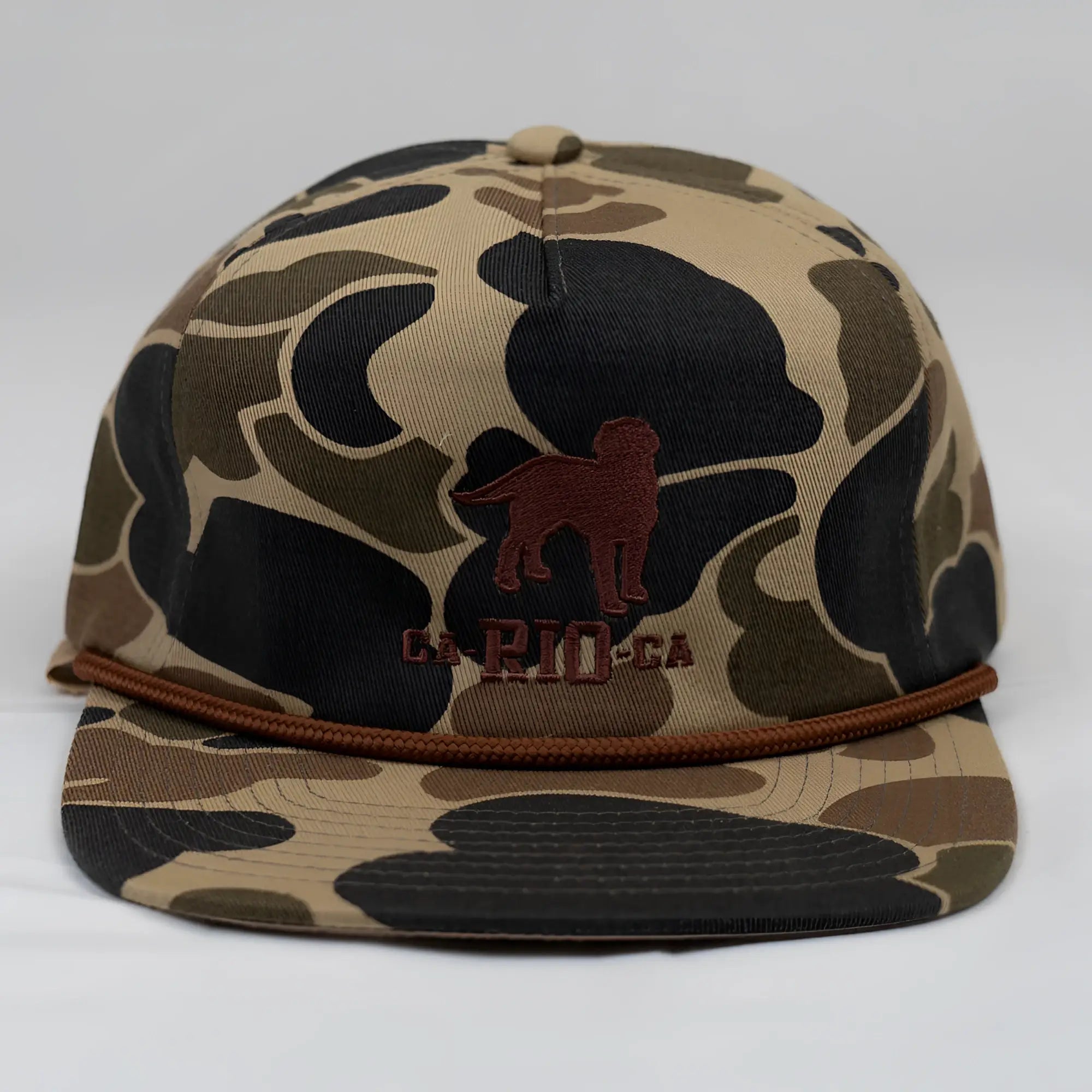 Old school camo unstructured rope hat in tan and black camouflage with brown embroidered dog silhouette and braided cord