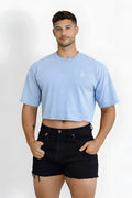 Light blue oversized relaxed crop top with small white logo on left chest and red tag at bottom hem