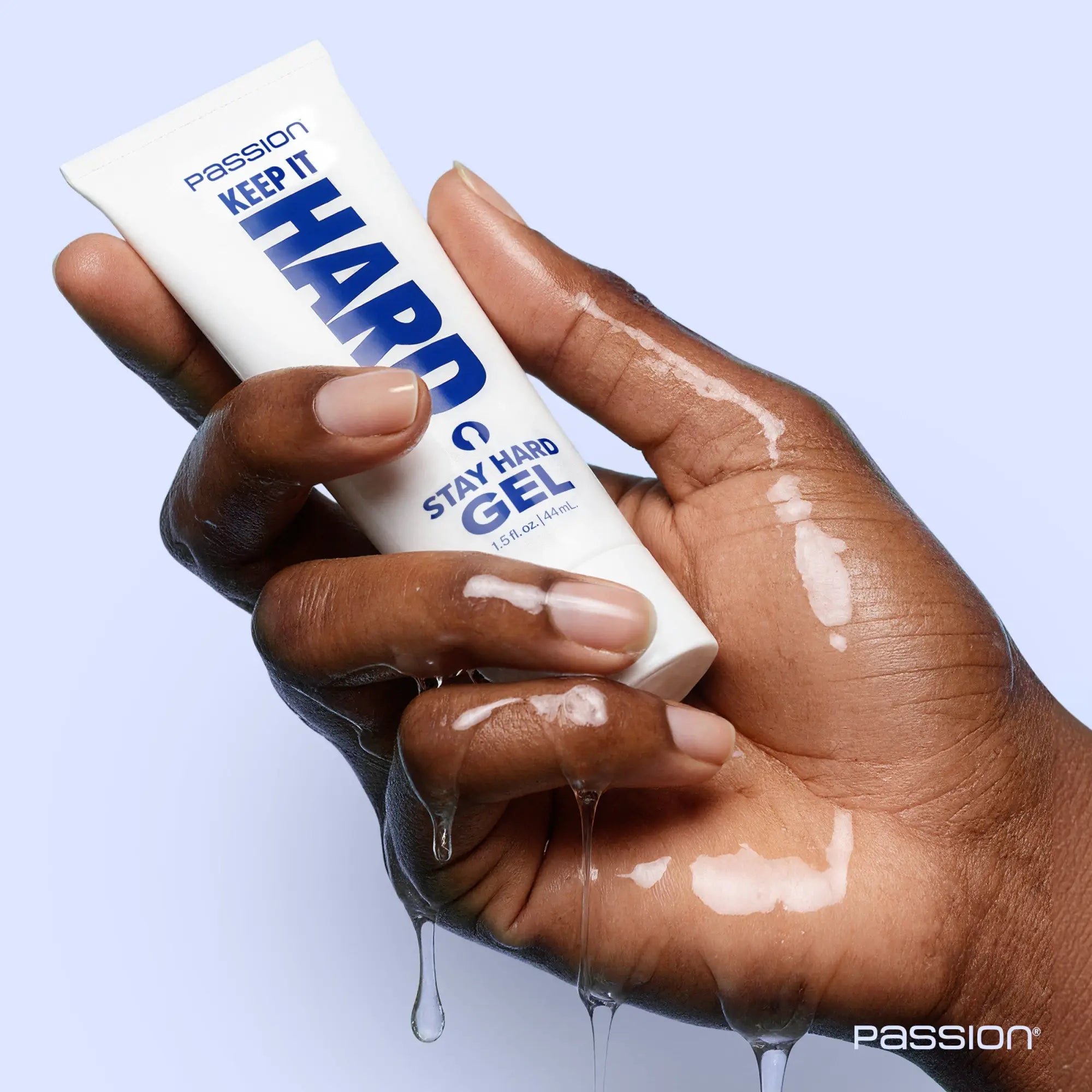 A hand holding a white 1.5oz tube of Passion Keep It Hard Stay Hard Gel, with clear gel dripping from the palm.