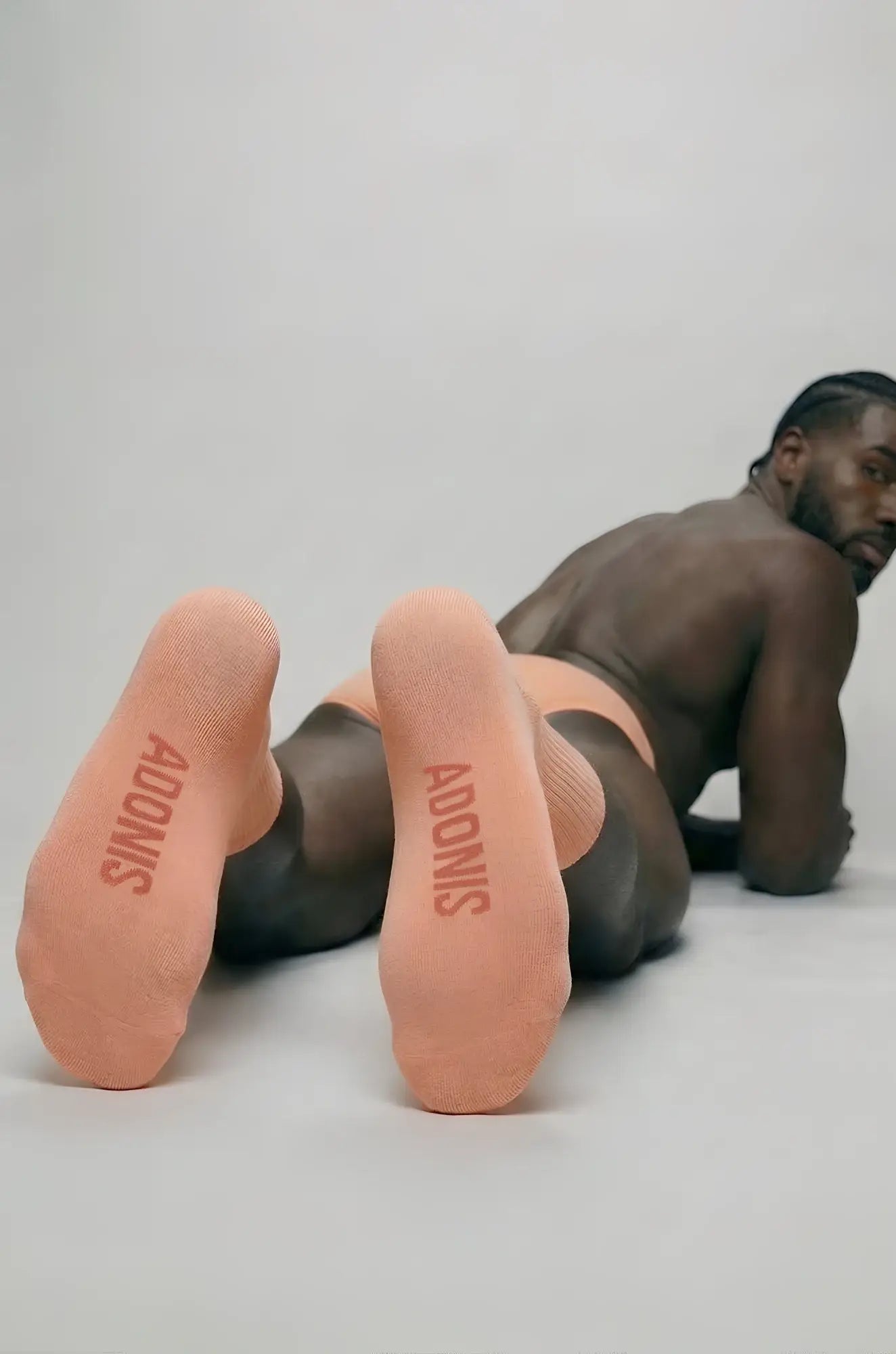 Peach cream crew socks featuring peach-colored fabric with adonis printed in bold red on the soles back side view