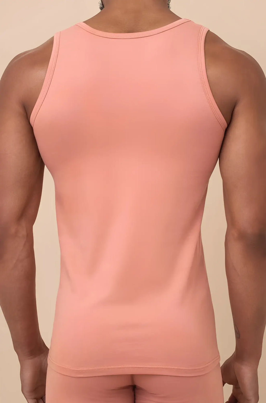 A soft pink peach cream tank top with a form-fitting seamless design and a simple round neckline