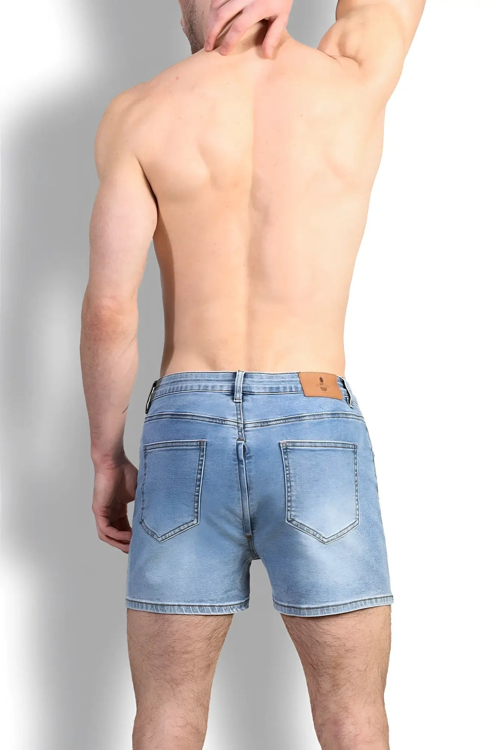 Back view of peek-a-boo denim shorts in light wash with classic pockets and brown leather brand patch