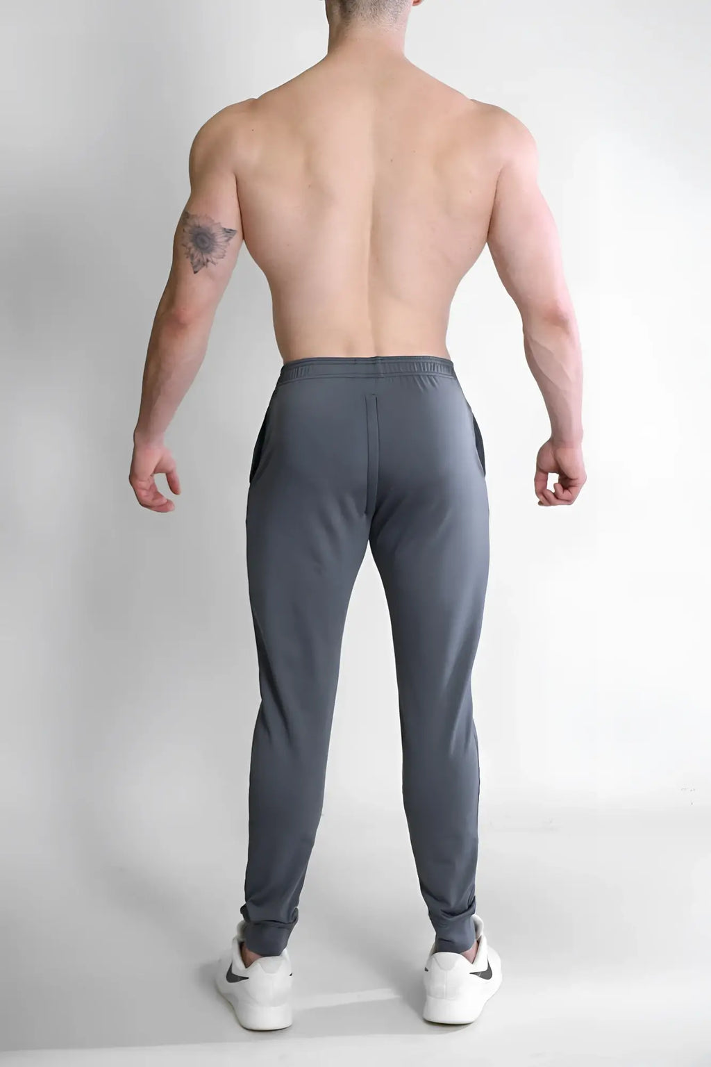 Dark grey peek-a-boo joggers with a sleek tapered fit and subtle side pockets in soft athletic fabric