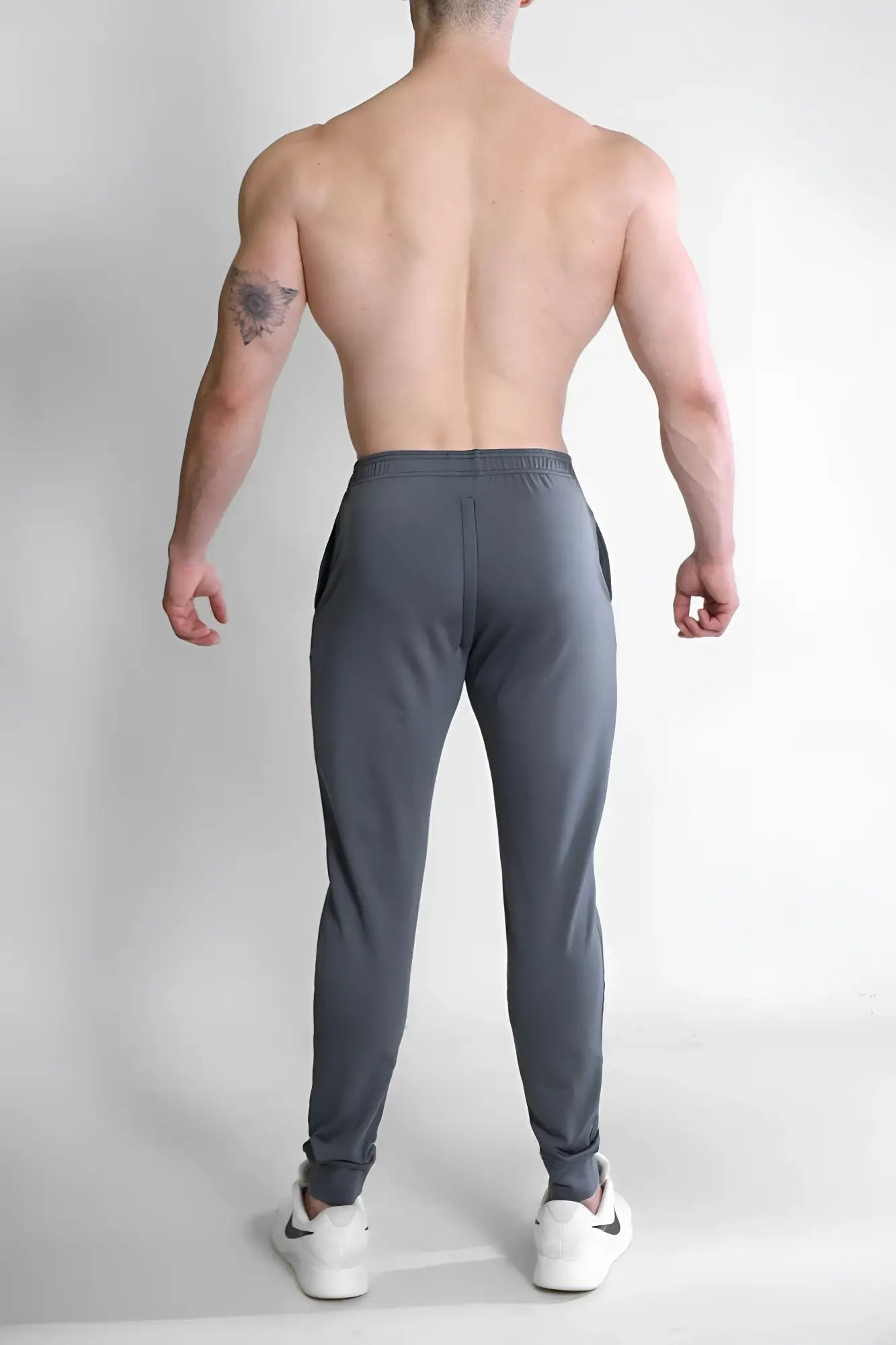 Dark grey peek-a-boo joggers with a sleek tapered fit and subtle side pockets in soft athletic fabric