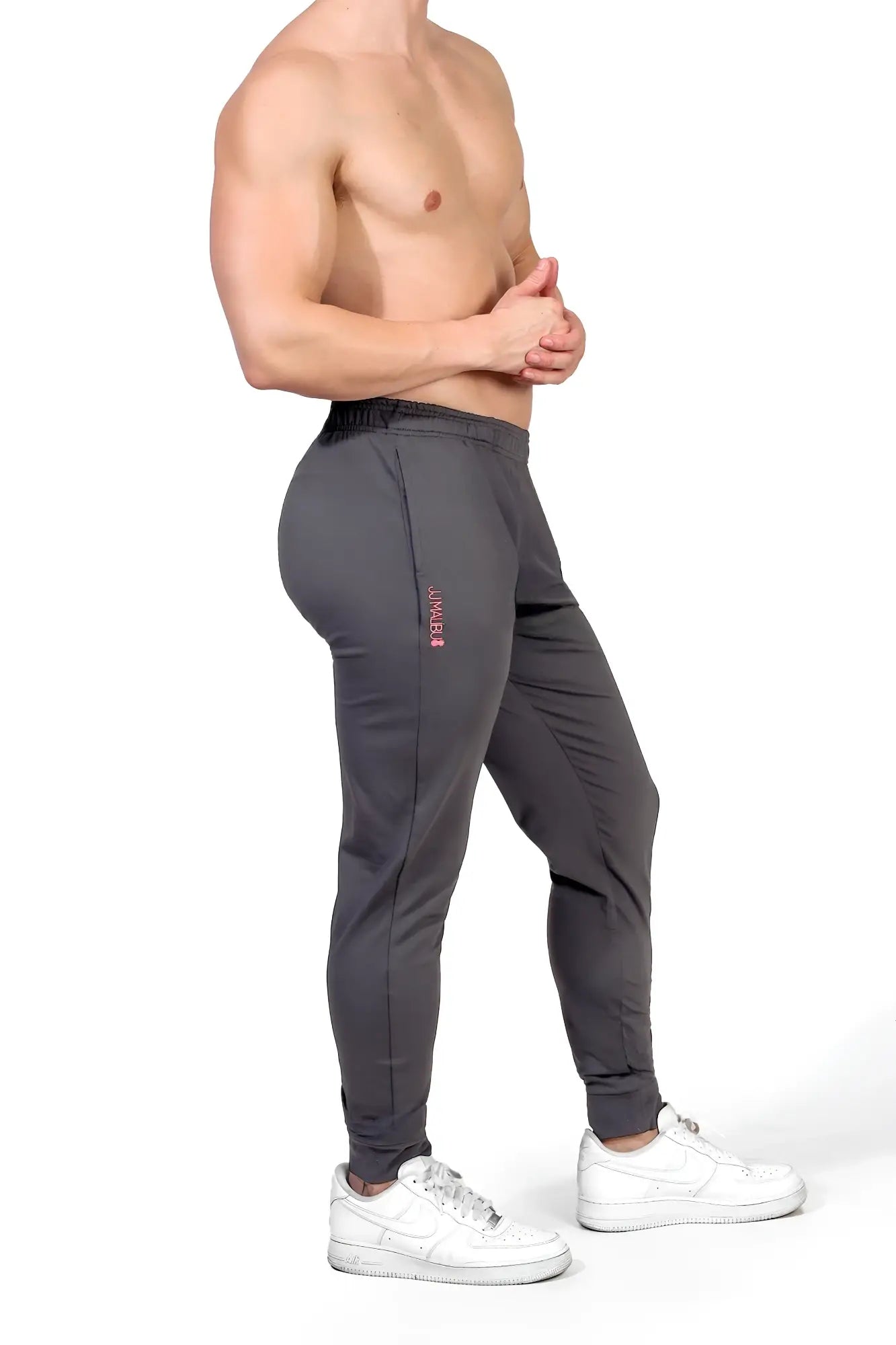 Dark grey peek-a-boo joggers with slim fit and subtle pink branding on the side seam for athletic wear