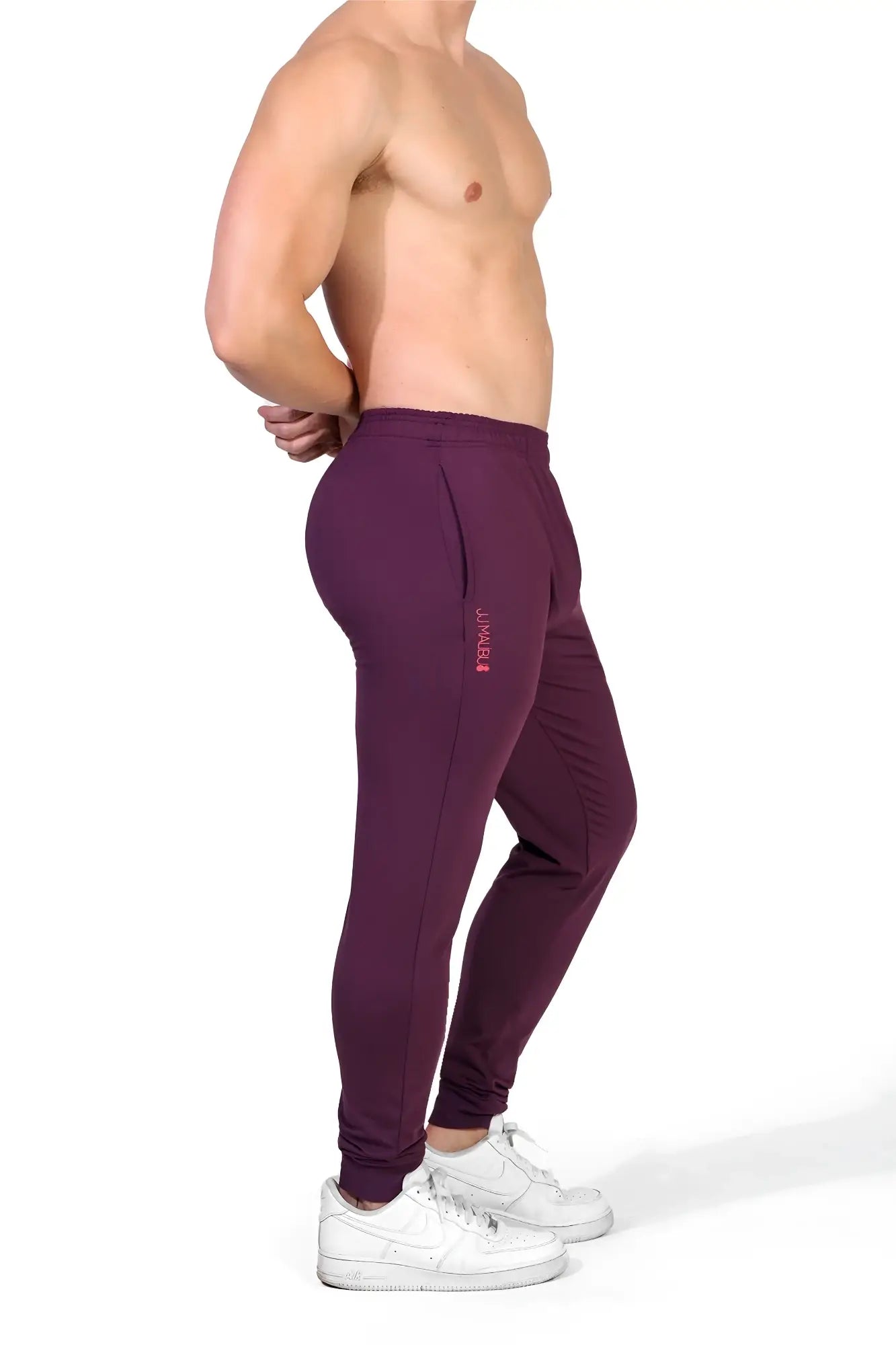 Peek-a-boo joggers in plum purple are mauve form-fitting pants with elastic cuffs and a subtle side logo
