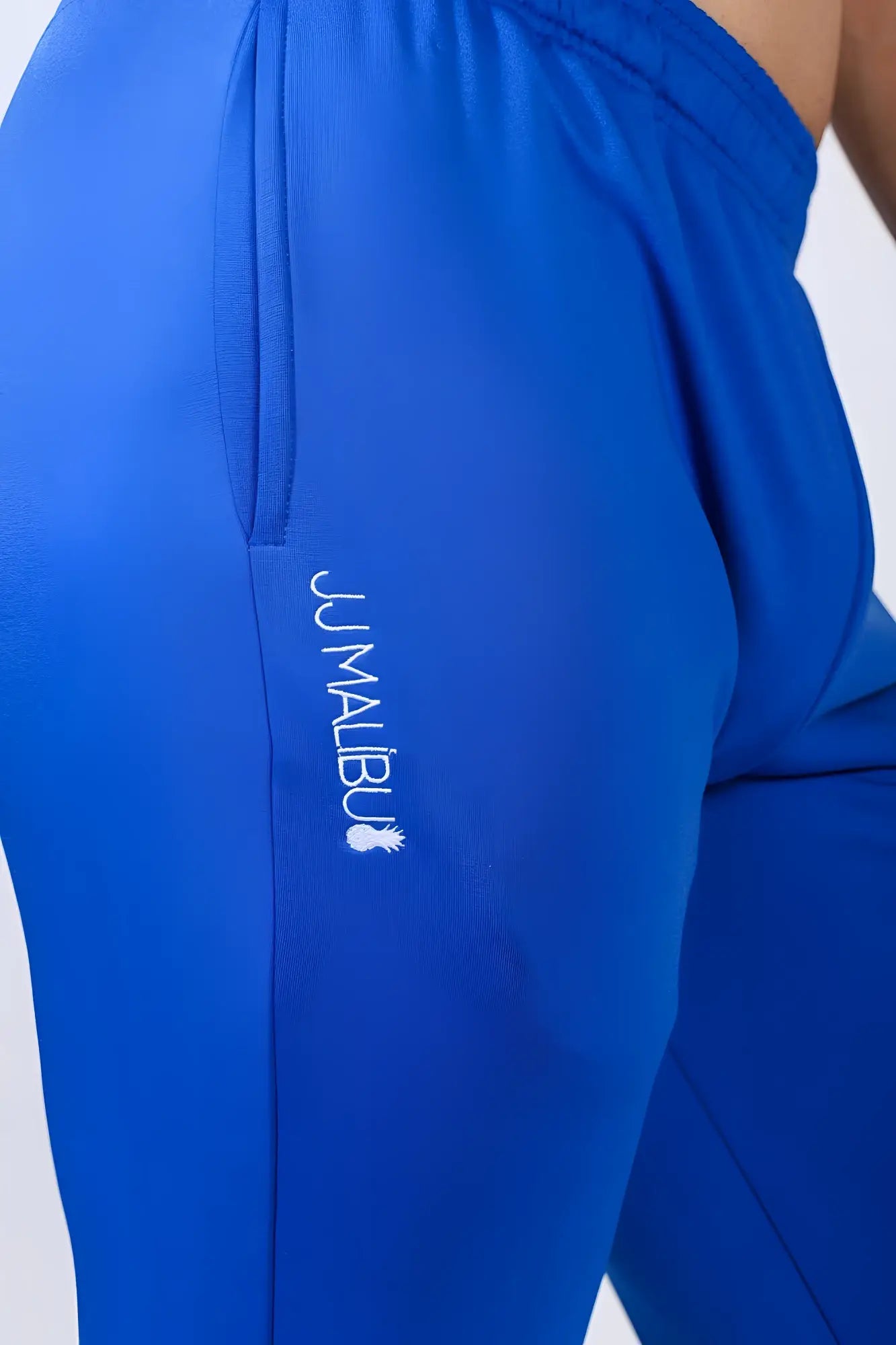 Bright royal blue peek-a-boo joggers with subtle textured fabric and jumalibu brand embroidery along the side seam