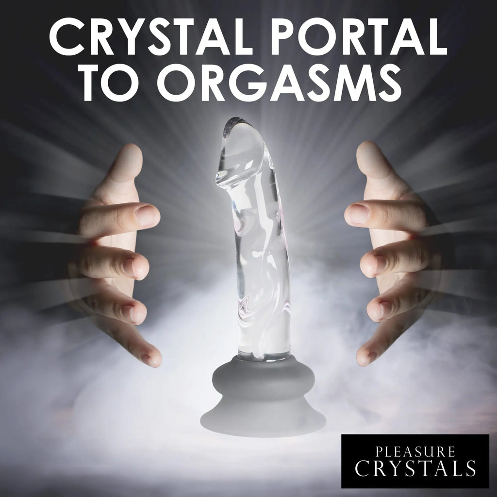 Pleasure Crystals clear glass dildo with a grey silicone suction base, held between two hands in a misty light.