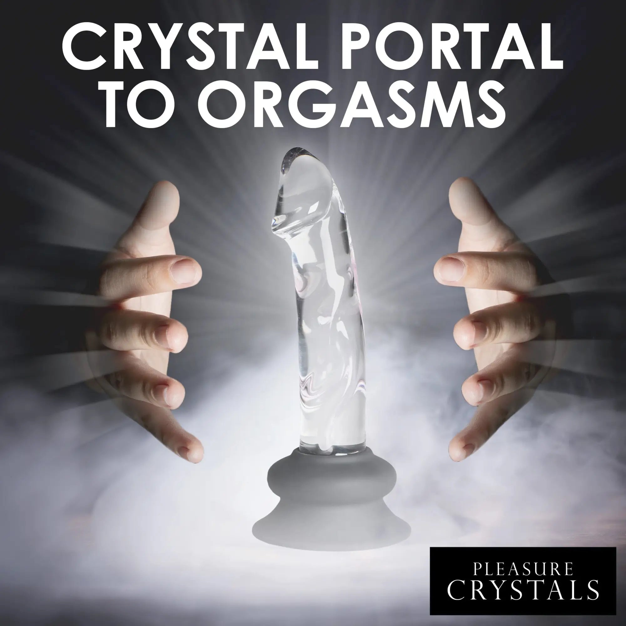 Pleasure Crystals clear glass dildo with a grey silicone suction base, held between two hands in a misty light.
