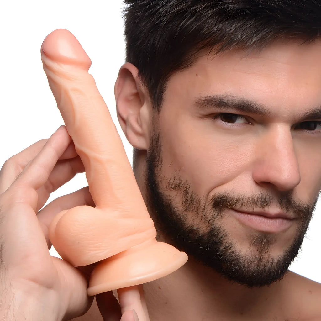 A man holding a light-toned, realistic 6.5-inch Pop Peckers dildo with detailed shaft, balls, and a suction base.