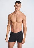 Black seersucker swim shorts with mesh lining featuring sleek minimalist design and single button waistband closure