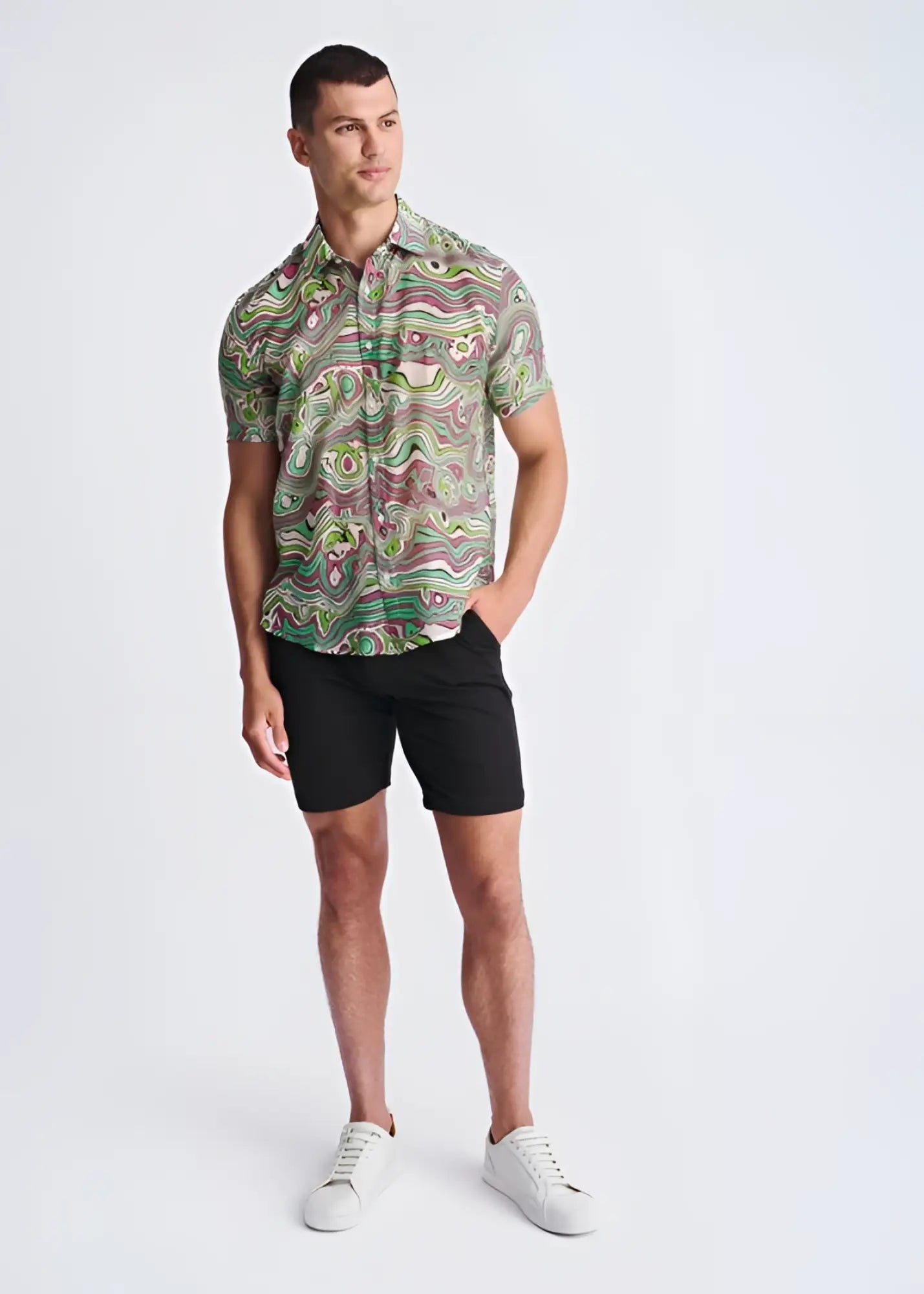 A man wearing a swirls lightweight cotton silk short-sleeved shirt with green pink and beige abstract pattern