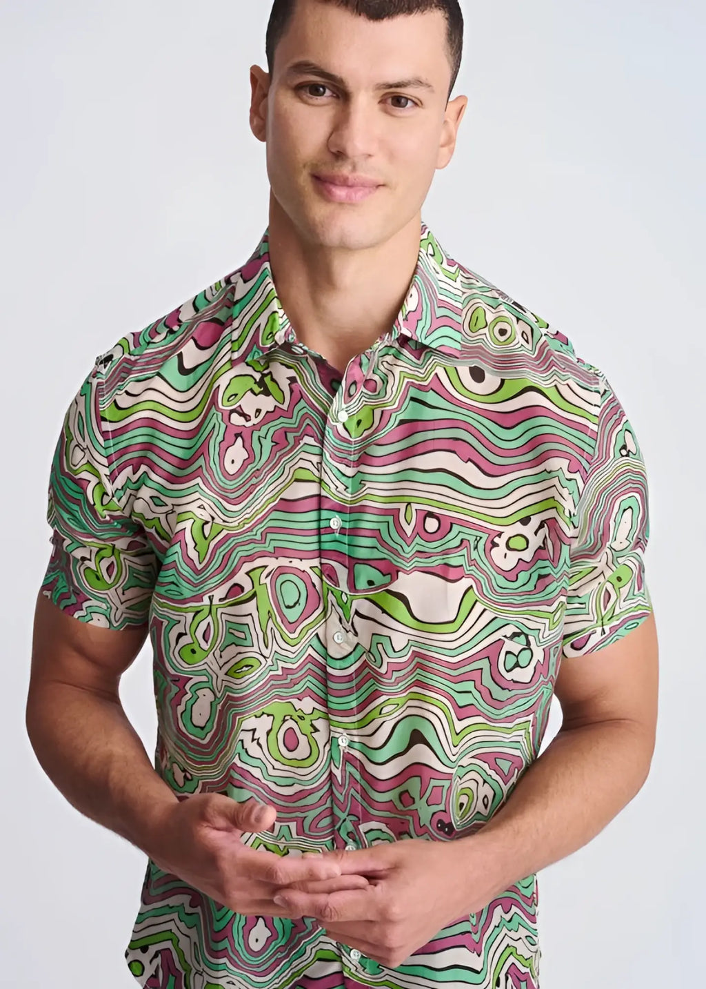 A vibrant short-sleeved button-up shirt with psychedelic green pink and white swirls in lightweight cotton silk