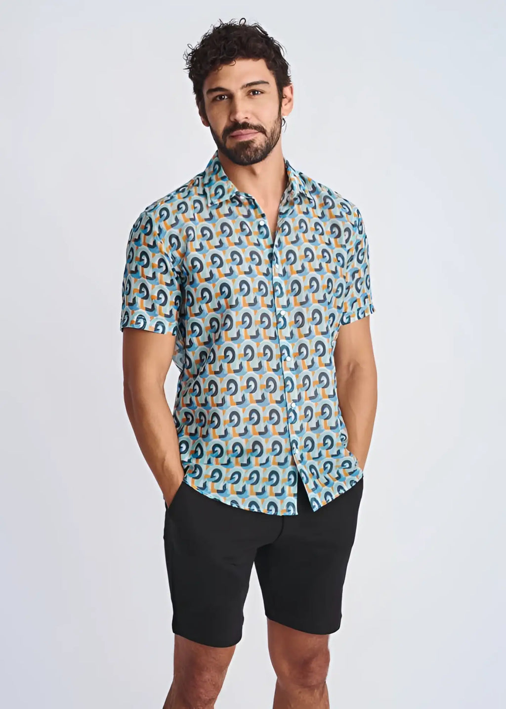 A man wearing a swirls lightweight cotton silk short-sleeved shirt with blue teal and orange geometric pattern