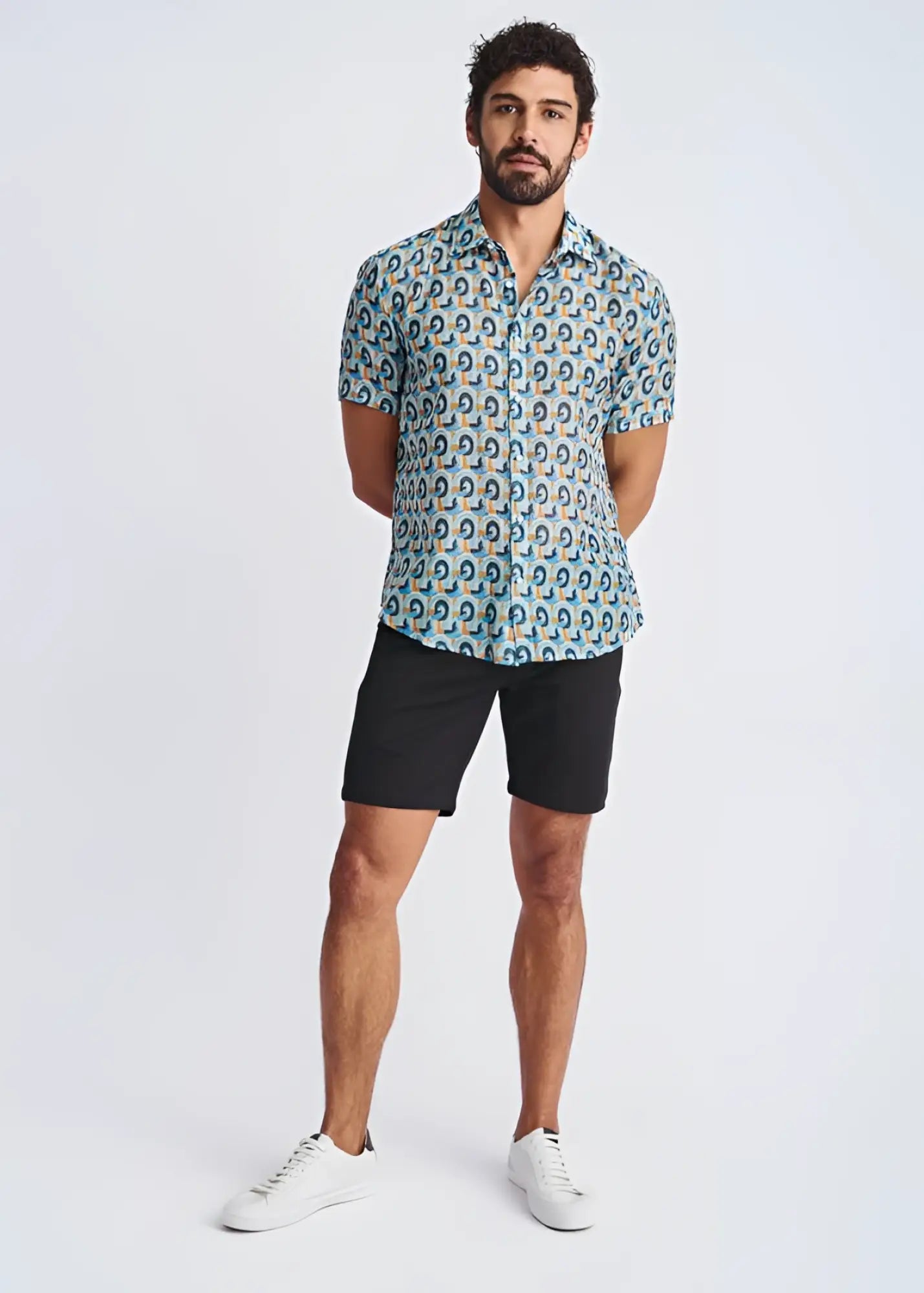 A man wearing a swirls lightweight cotton silk short-sleeved shirt with a blue green and yellow circular pattern