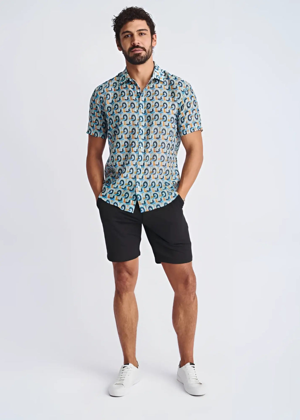 A man wearing a swirls lightweight cotton silk short-sleeved shirt with blue teal and beige circular patterns