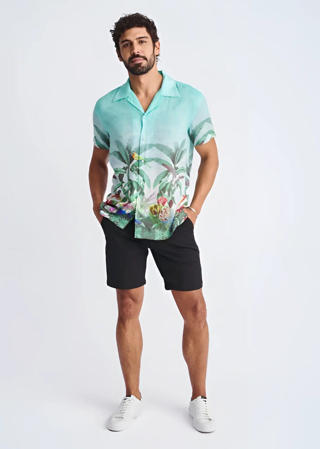 A men’s short-sleeved modal shirt in vibrant turquoise with a tropical print of foliage and colorful birds