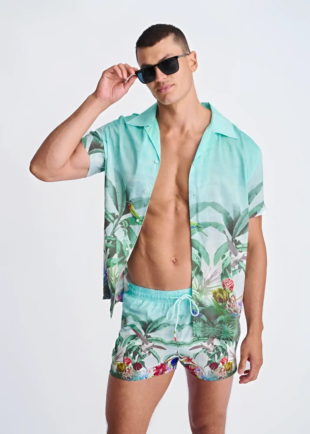 Turquoise tropics print swim shorts with mesh lining featuring palm leaves and birds paired with a matching shirt