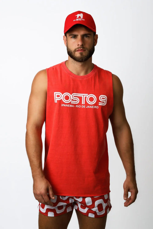 Man wearing a red sleeveless tank top with white posto 9 lettering and smaller text below in a posto 9 ipanema tee