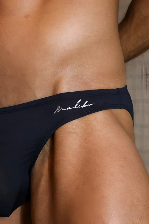 Navy blue malibu swim trunks with white cursive logo stitching and premium modal scrunch-back cheeky brief in black