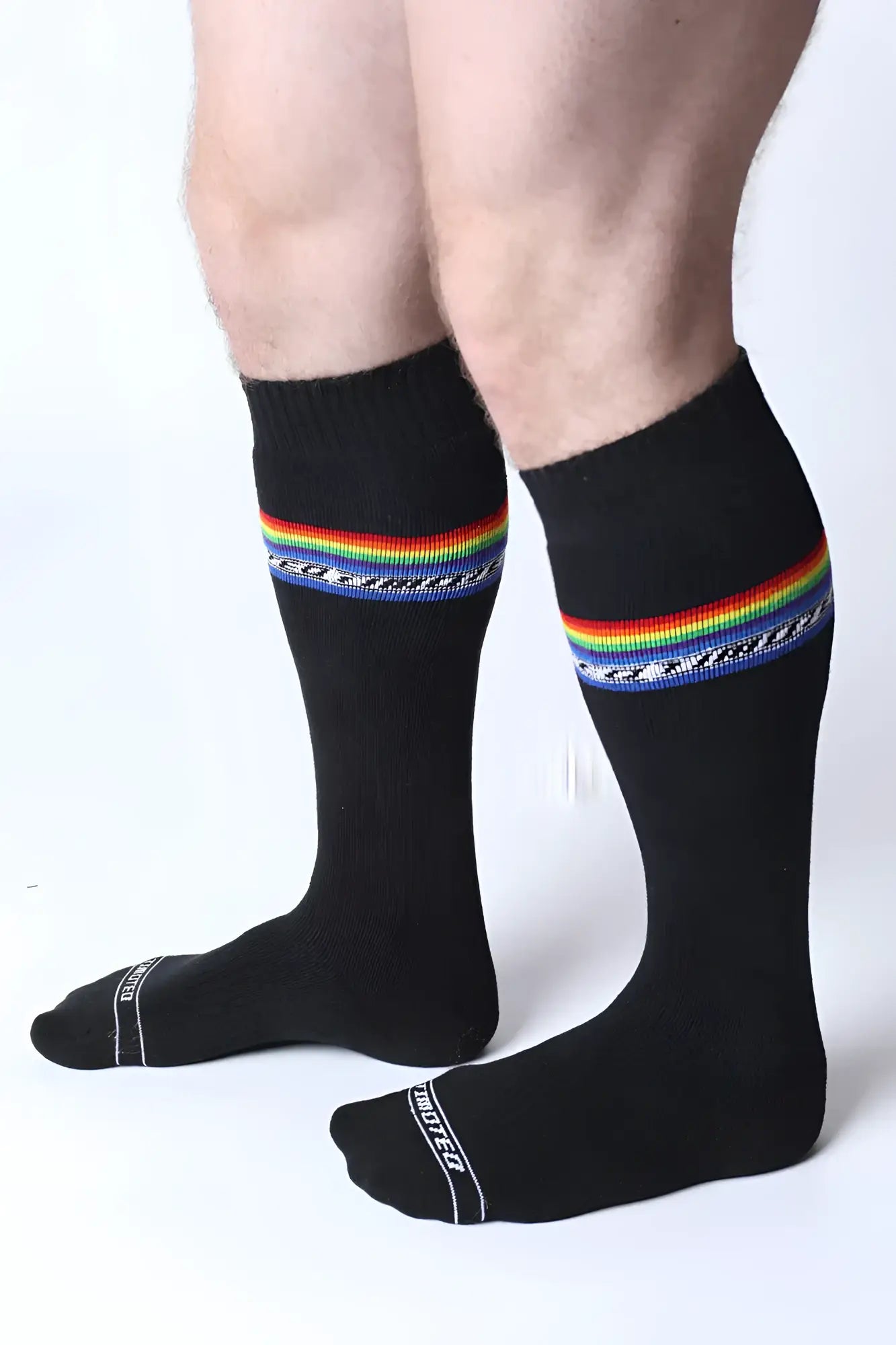 Pride knee high black socks with vibrant rainbow stripe decorative blue pattern and white text on toe area