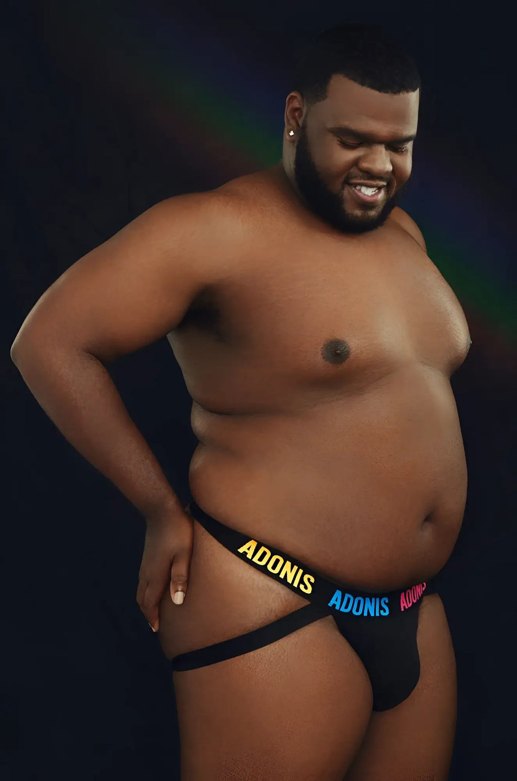 Black pride365 jockstrap briefs with adonis printed in yellow and blue lettering on the front