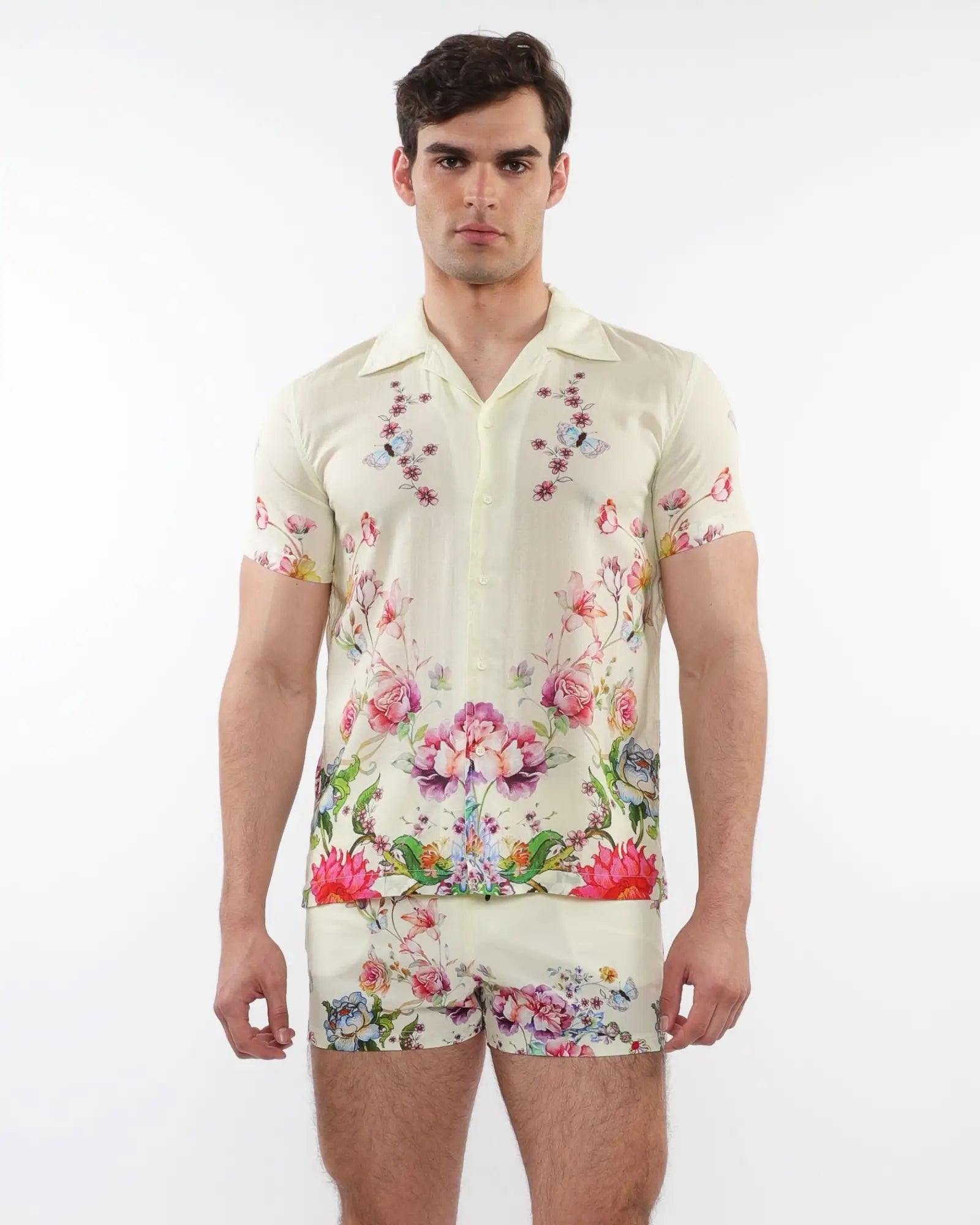 A man wearing a cream printed short-sleeved woven modal border shirt with vibrant floral and butterfly patterns
